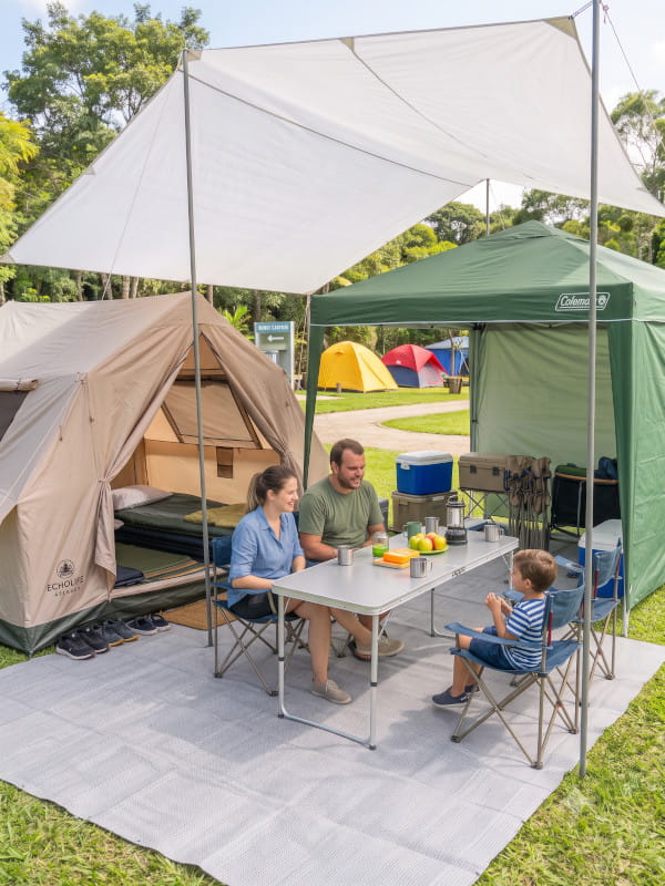 Espaço de camping limpo e organizado com barraca, equipamentos arrumados e área de descanso estruturada.